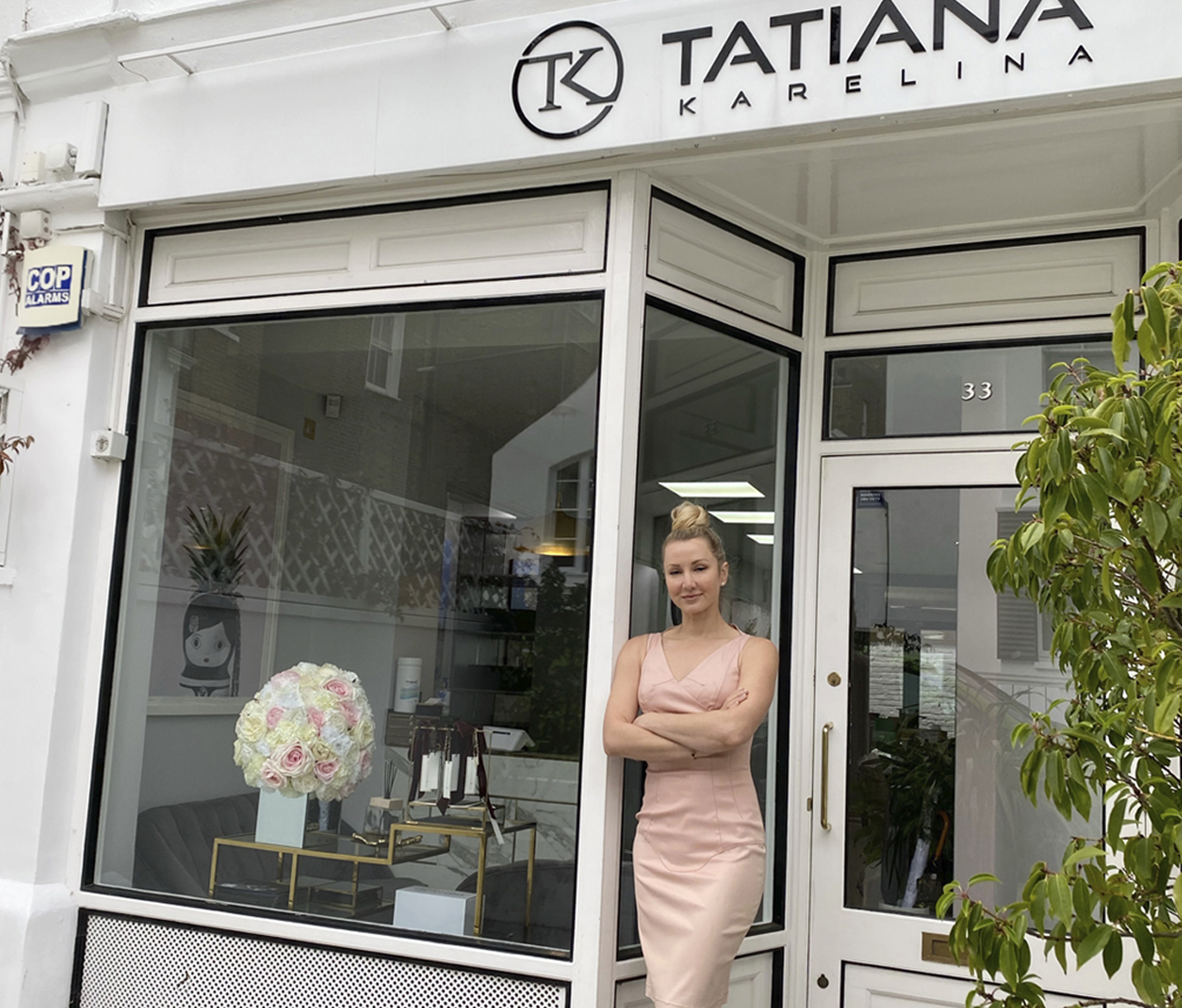 High Quality Hair Extensions | Tatiana Karelina leaning on the wall while standing in front of her London salon. 